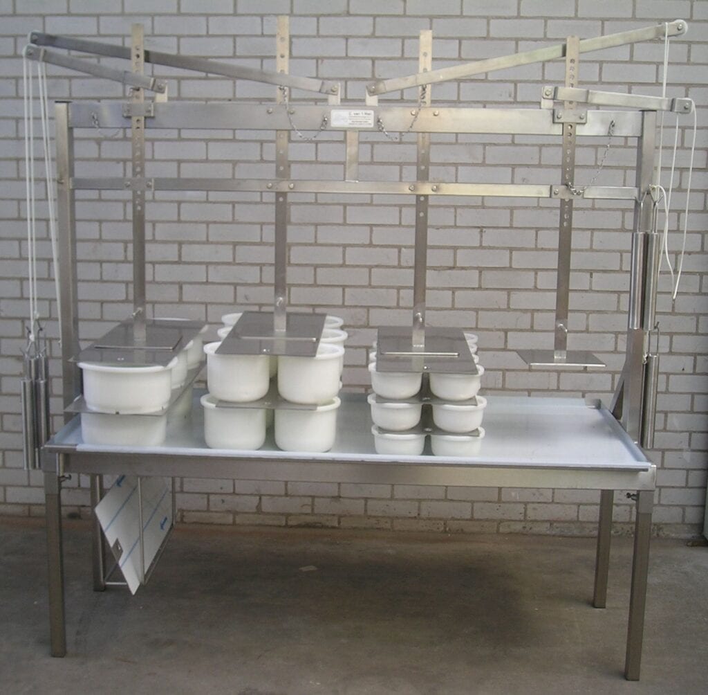 A large metal table with multiple plastic containers, set against a brick wall.