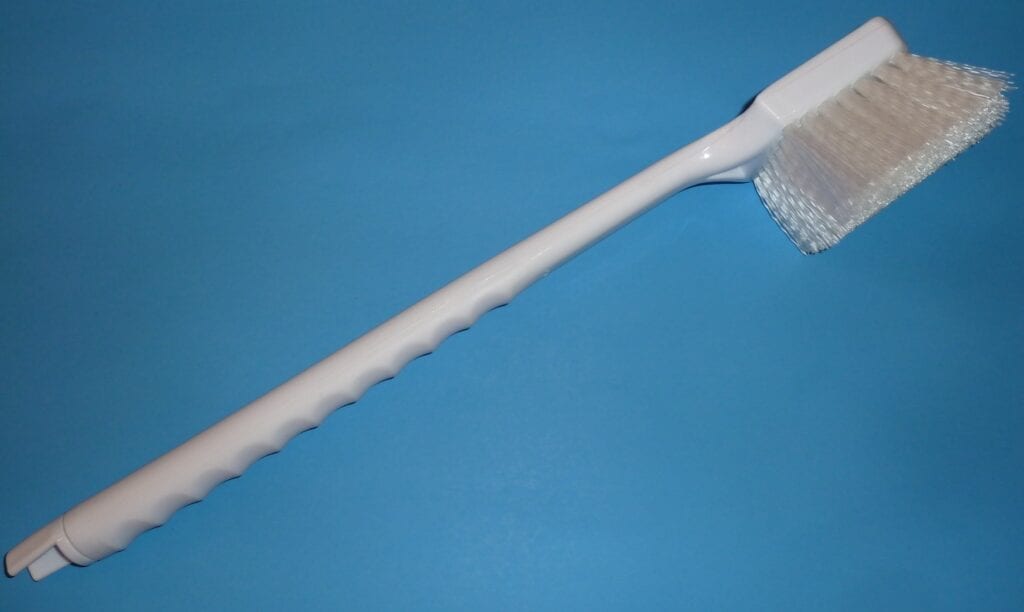 Close-up of a white plastic bottle brush on a blue background.