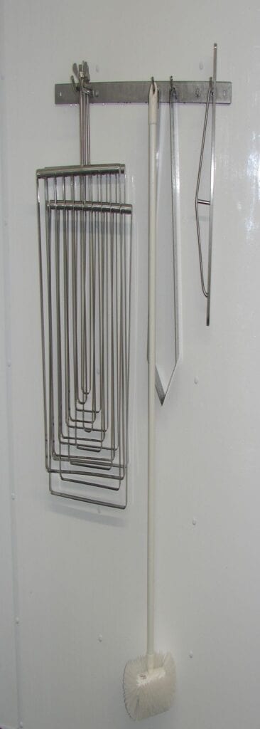 A series of metal wire hooks arranged in descending order on a wall.
