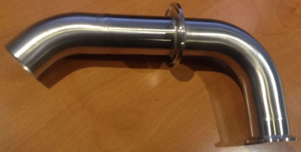 Close-up of a shiny metal pipe joint on a wooden surface.