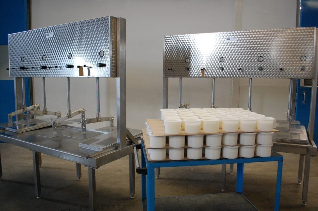 Industrial machinery with multiple rows of white containers on a blue cart.