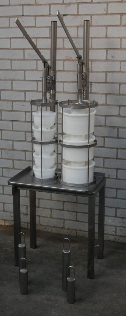 Stacked white containers secured with metal rings on a small black table.