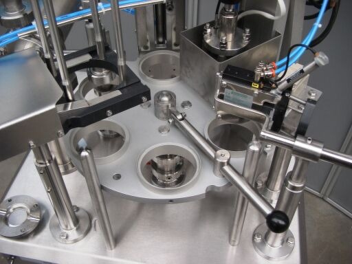 Close-up of a stainless steel machine with rotating components and levers.