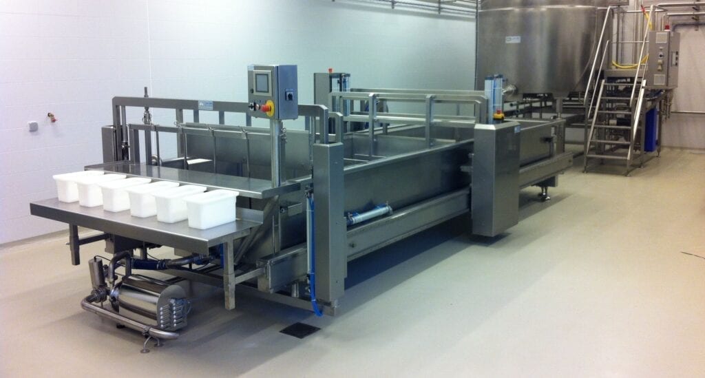 Industrial machine packaging white containers in a clean facility.